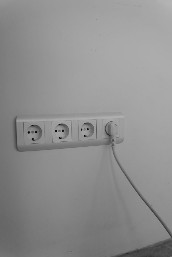 A clean and minimalist wall socket with a single plug connected, emphasizing modern interior design.